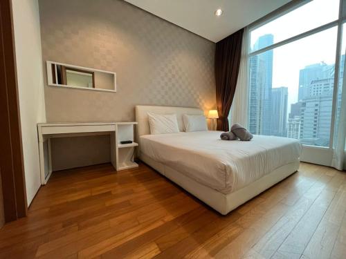 Soho Suites KLCC في كوالالمبور: غرفة نوم مع سرير مع دمية دب عليها