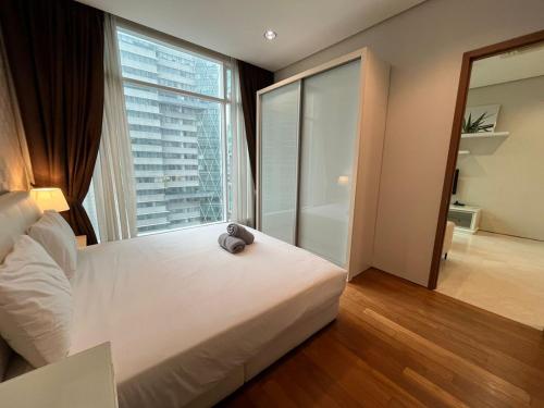 Soho Suites KLCC في كوالالمبور: غرفة نوم بسرير ابيض ونافذة كبيرة