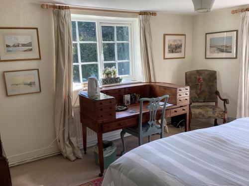 um quarto com uma secretária, uma cama e uma janela em Garden Cottage B&b em Penton Mewsey