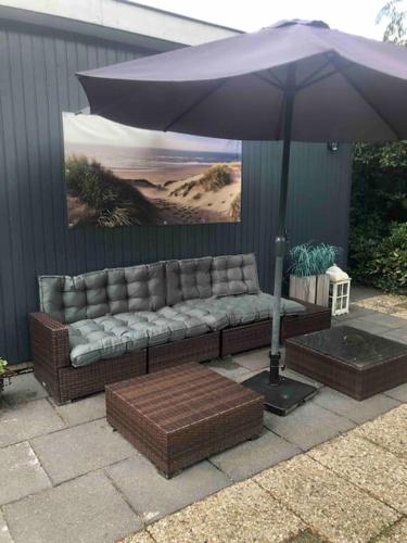 a couch sitting under an umbrella on a patio at Heerlijk huisje op de Veluwe in Ermelo