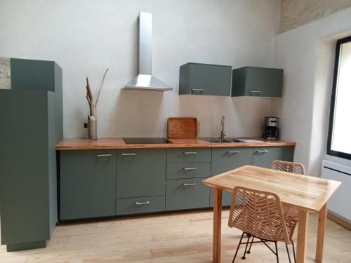 cocina con armarios verdes y mesa de madera en Maison en pierre restaurée avec jardin, en Auch