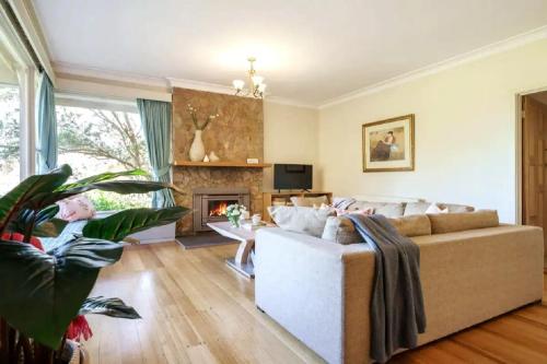 een woonkamer met een bank en een open haard bij Chatsworth House and Cottage in Balnarring