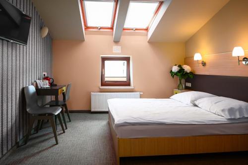 a bedroom with a bed and a desk and a window at Hotel Kazimierz III in Kraków
