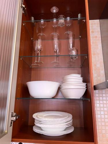 ein Schrank mit Tellern, Gläsern und Geschirr in der Unterkunft Jurincom apartmens Zamecky Vrch in Karlsbad