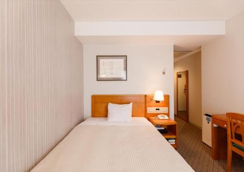 a bedroom with a bed and a desk with a telephone at Kanazawa New Grand Hotel Premier in Kanazawa