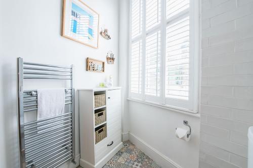 a white bathroom with a window and a towel rack at Pass the Keys - Modern & Stylish Garden Home in Islington in London