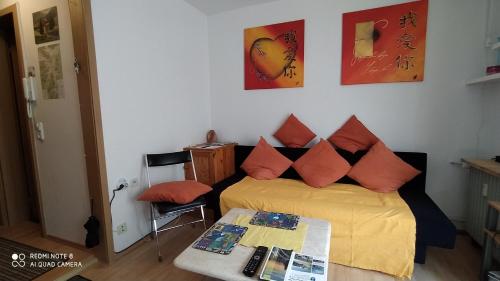 a bedroom with a bed with orange pillows and a table at Tiny Flat Baiersbronn in Baiersbronn