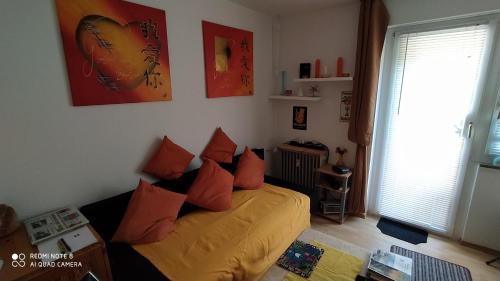 a bedroom with a bed with orange pillows on it at Tiny Flat Baiersbronn in Baiersbronn