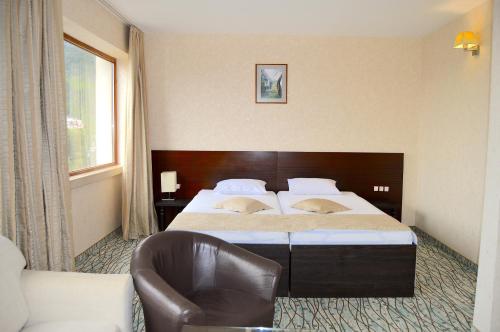 a hotel room with a bed and a chair at Hemus Hotel - Vratza in Vratsa