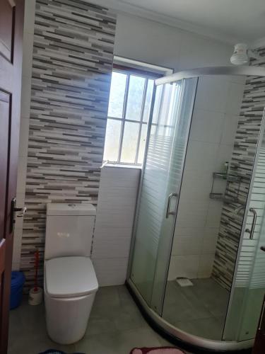 a bathroom with a toilet and a glass shower at Stay with Eve in Kitale