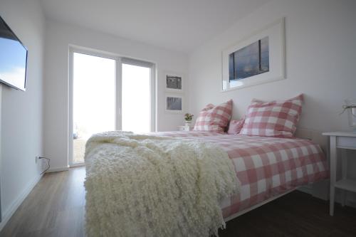 a white bedroom with a bed with a plaid blanket at Ferienwohnung OstseeBrise in Olpenitz