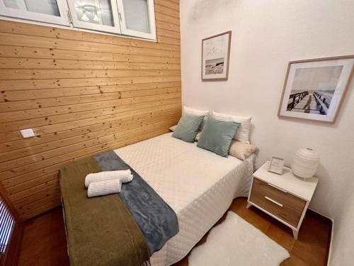 een kleine slaapkamer met een bed en een houten muur bij Preciosas vistas al mar en Castelldefels in Castelldefels
