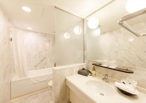 a white bathroom with a sink and a shower at Kanazawa New Grand Hotel Premier in Kanazawa