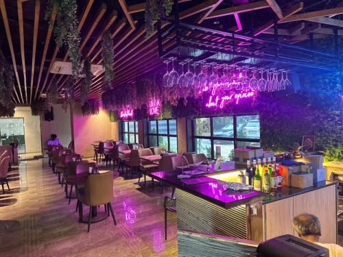 a bar in a restaurant with purple lighting at Hotel Merakee - Near Dahisar Mira Road Mumbai in Mumbai