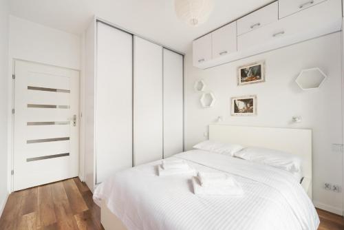 a white bedroom with white walls and a large bed at Włochy Rakowska Comfort Apartment in Warsaw