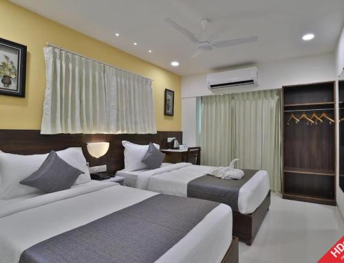 Habitación de hotel con 2 camas y TV en Leo Hotel, en Ahmedabad