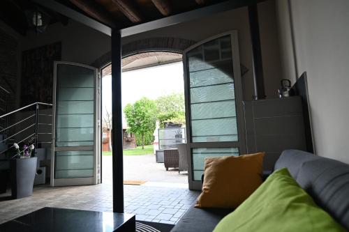 een woonkamer met een bank en een glazen deur bij CA CENTOSA ARTISTIC HOUSE villa storica ristrutturata con patio e giardino in Cittadella