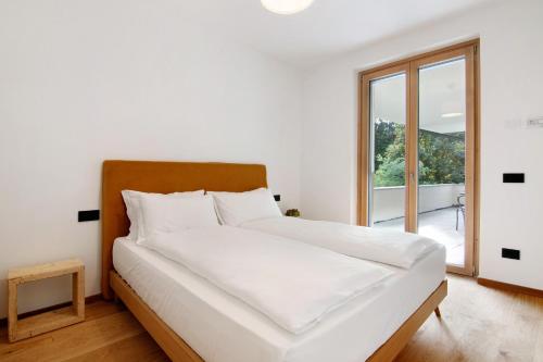 La villa del lago in terrazzo في كوليكو: غرفة نوم بسرير أبيض مع نافذة كبيرة