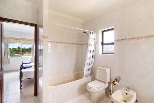 a bathroom with a toilet and a tub and a sink at Casa das Areias in Porches