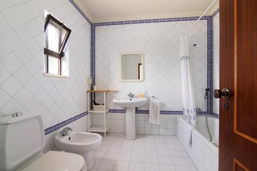 a white bathroom with a toilet and a sink at Casa das Areias in Porches