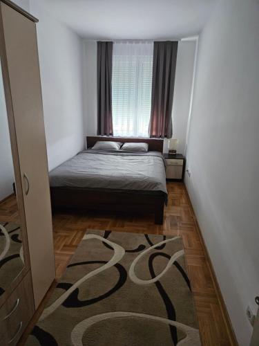 a small bedroom with a bed and a rug at Banjica in Jajinci