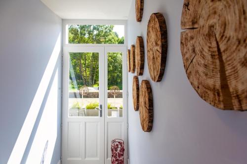a hallway with a white door and wooden plates on the wall at LA BATISSE l'arbre gris in Le Grand-Abergement