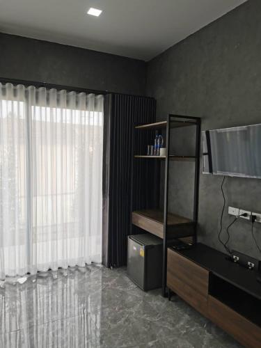 a living room with a large window and a television at NST Boutique เอ็นเอสทีบูทีค in Ban Pak Phun