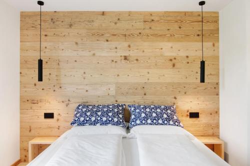 a bed with blue and white pillows and a wooden wall at La Villa del lago in Colico