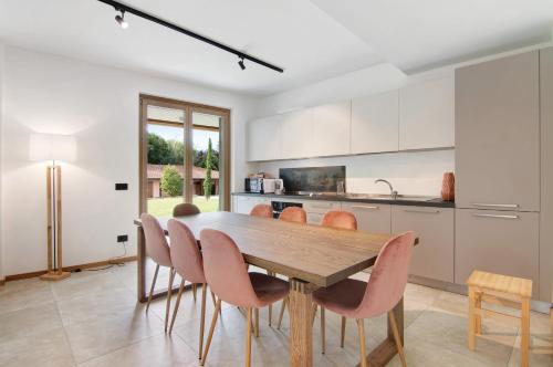 a kitchen with a wooden table and pink chairs at La Villa del lago in Colico
