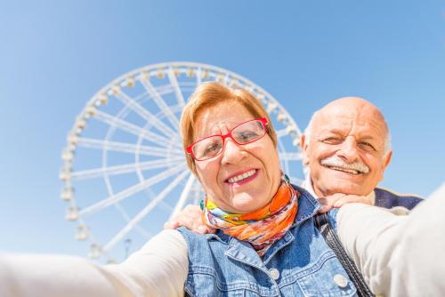 an older couple standing in front of a ferris wheel at Beautiful 8 Berth Caravan With Decking At Naze Marine Park, Essex Ref 17184P in Walton-on-the-Naze