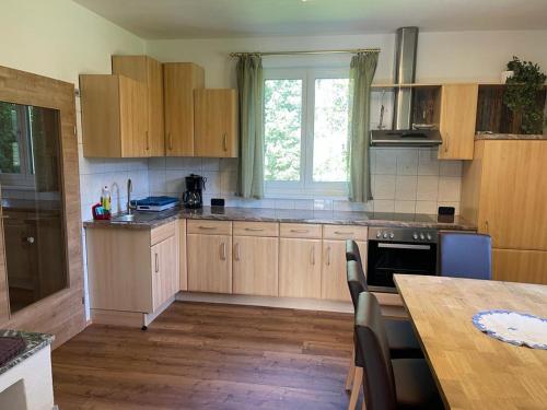 eine Küche mit Holzschränken, einem Tisch und einem Fenster in der Unterkunft Ferienhaus Murtal in Weißkirchen in Steiermark