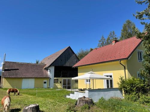 a yellow house with a horse grazing in the yard at Ferienhaus Murtal in Weißkirchen in Steiermark