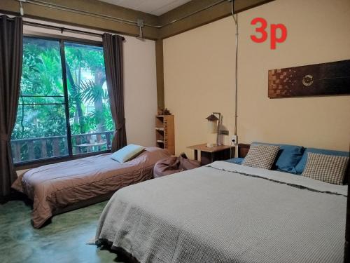 um quarto com 2 camas e uma grande janela em Oldy De Garden em Chiang Mai