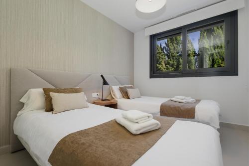 um quarto com 2 camas e uma janela em Luxury Duplex Penthouse with sea views walking distance to the beach in Los Miradores del Sol em Estepona