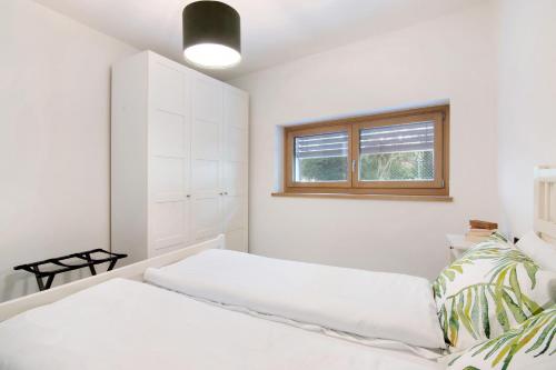 a white bedroom with a bed and a window at La villa del lago in giardino in Colico