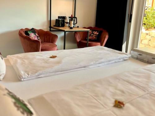 a bedroom with two beds and two chairs and a table at ROSER Suiten in Gengenbach