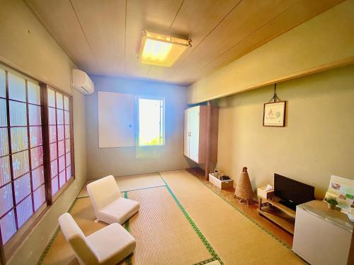 a living room with white chairs and a tv at COCO TERRACE -Ocean View- in Ito