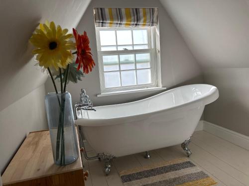 baño con bañera blanca y ventana en Stunning period cottage, en Wrington