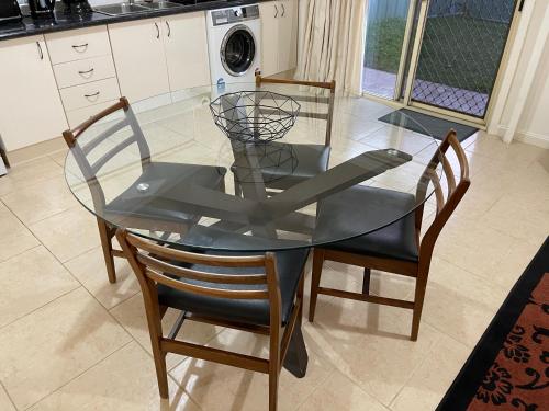 a glass dining room table with two chairs and a kitchen at Comfortable and well equipped Studio Apartment in Mudgee - Rest Easy Mudgee Studio in Mudgee