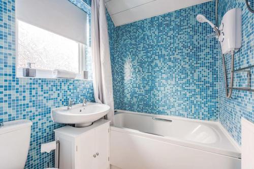 een blauw betegelde badkamer met een wastafel, een bad en een toilet bij Alexandra - WiFi Parking Garden in Walton le Dale