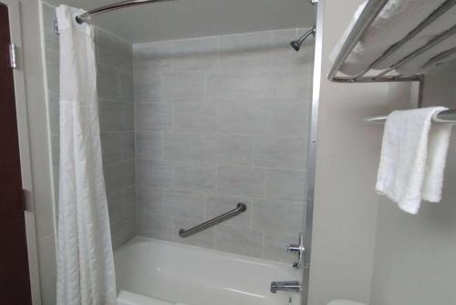a bathroom with a shower with a white tub at Super 8 Motel by Wyndham near Fort Lauderdale Arpt in Dania Beach