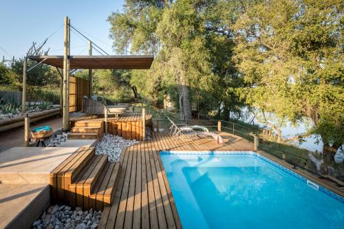 a swimming pool with a wooden deck next to a house at Bundox River Lodge in Hoedspruit