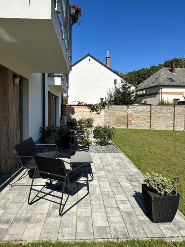 a patio with chairs and a table in a yard at Linden Apartman 002 - Adults Only in Mosonmagyaróvár