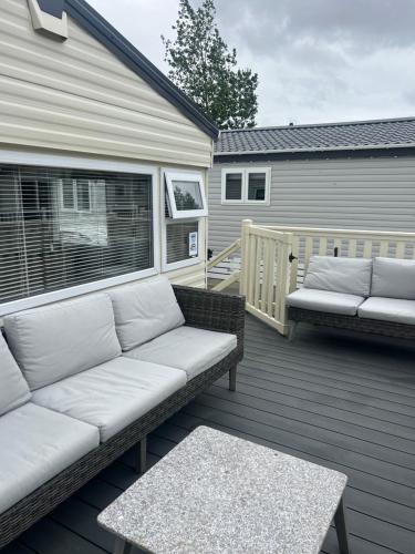 a patio with two couches and a table on a deck at Lovely 2-Bed Cabin in Birchington in Birchington