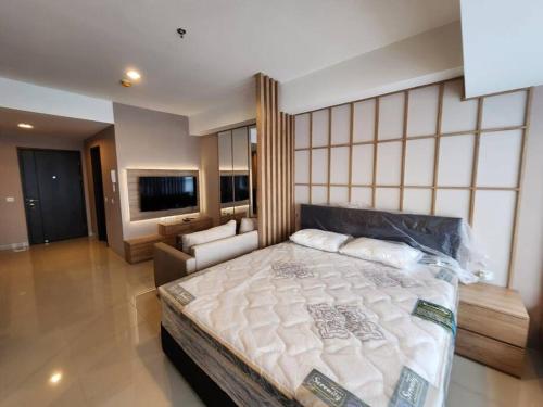 een slaapkamer met een groot bed en een bank bij Irvine Suites Lantai 26-I2618 in Cikarang