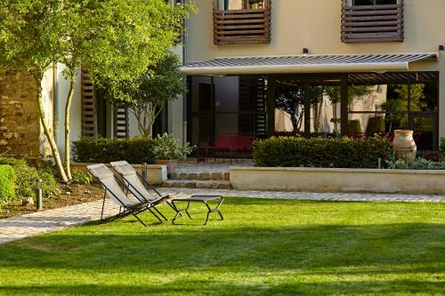 two chairs sitting in the grass in front of a house at Chambre d'hôtes Les Herbes Folles in Mauregard