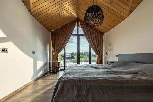 a bedroom with a large bed and a large window at Lielpīles in Radziņciems