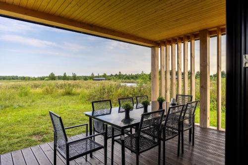 a table and chairs on a porch with a view of a field at Lielpīles in Radziņciems