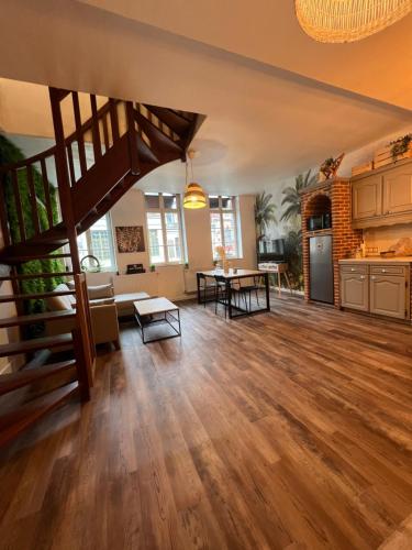 una gran sala de estar con suelo de madera y una escalera en La palmeraie - duplex 4 pers, en Condé-sur-lʼEscaut