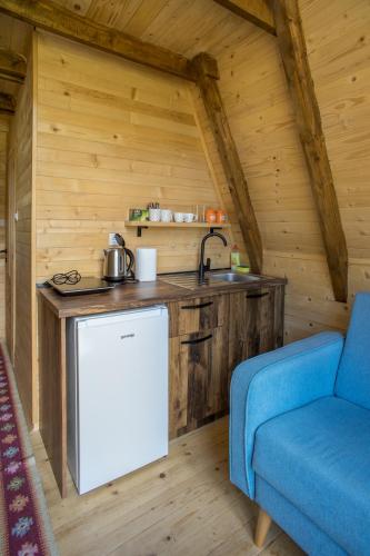 a kitchen in a log cabin with a sink and a blue couch at Mountain Houses Emilija in Žabljak